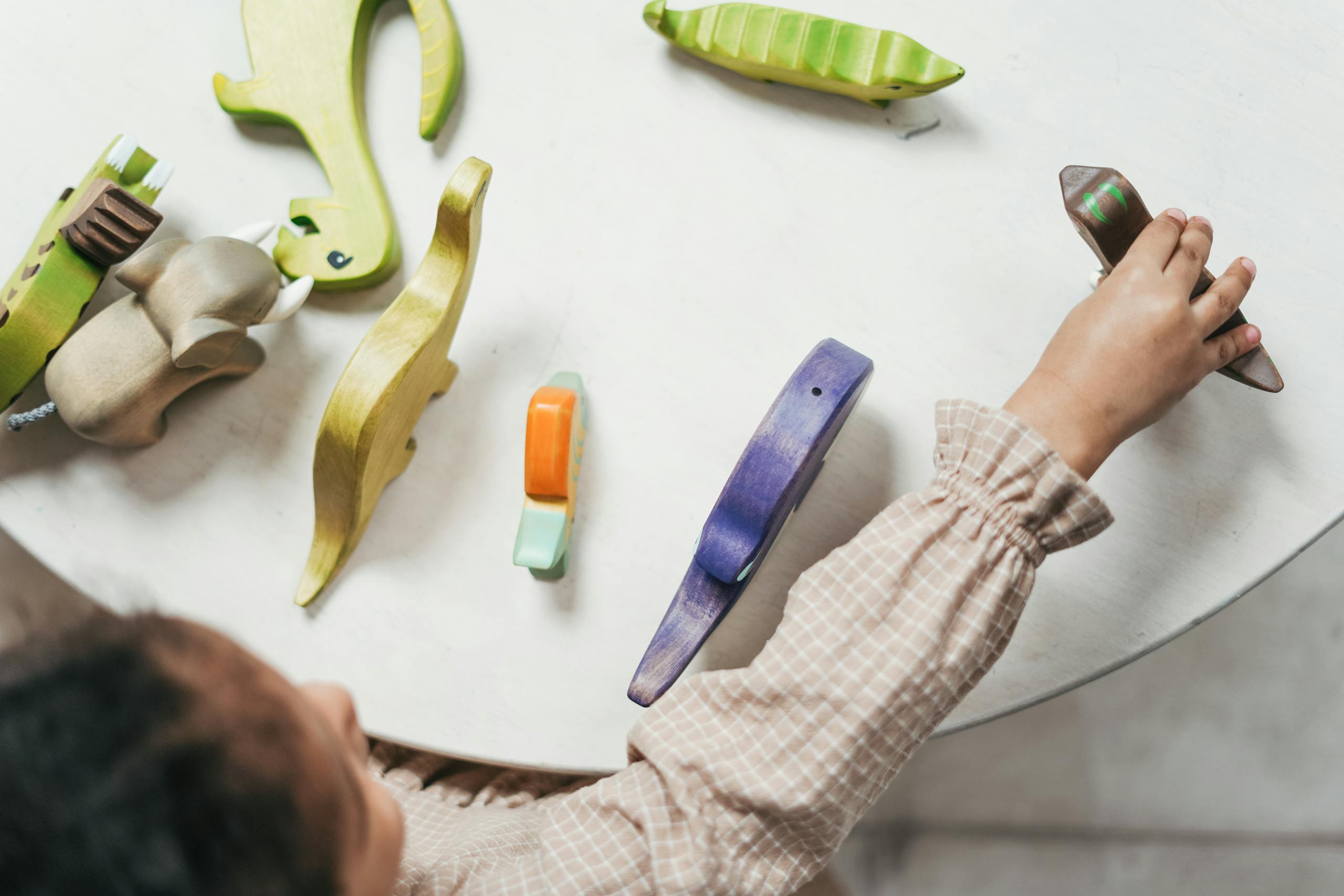 Child playing with colorful wooden toys in a playful indoor setting.